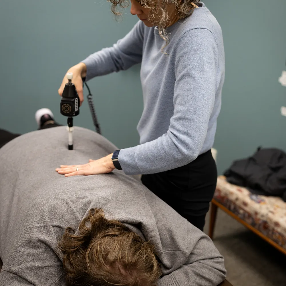Dr. Stacy using an Activator on a patient's lower back