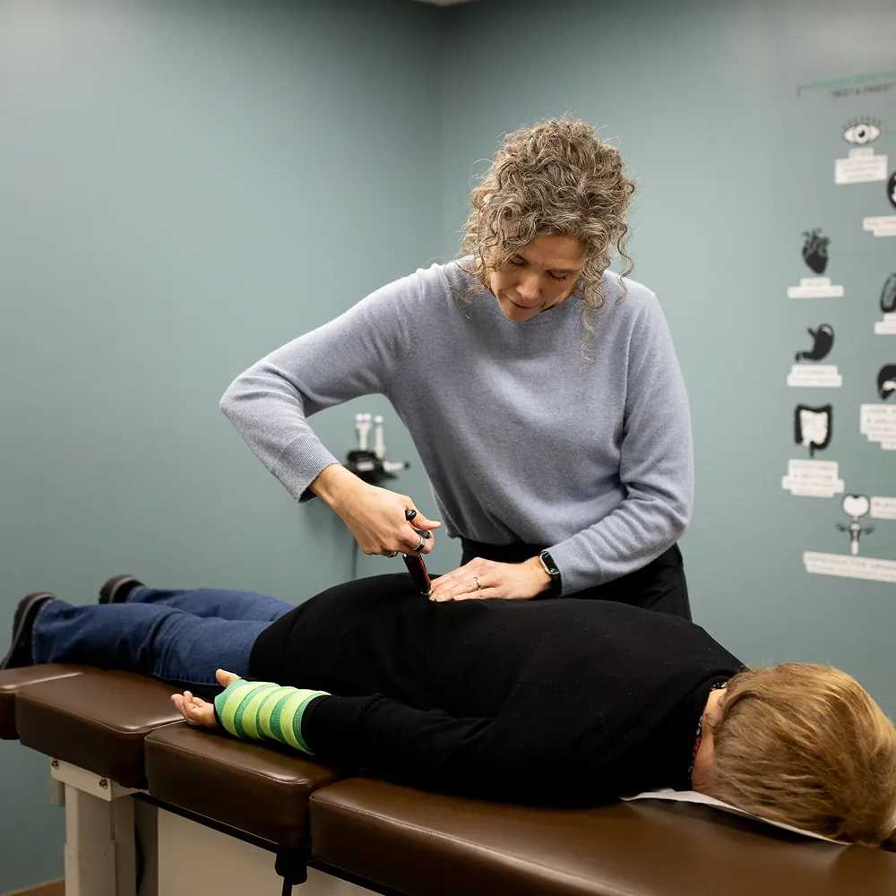 Dr. Stacy using an Activator instrument on a patient's upper back