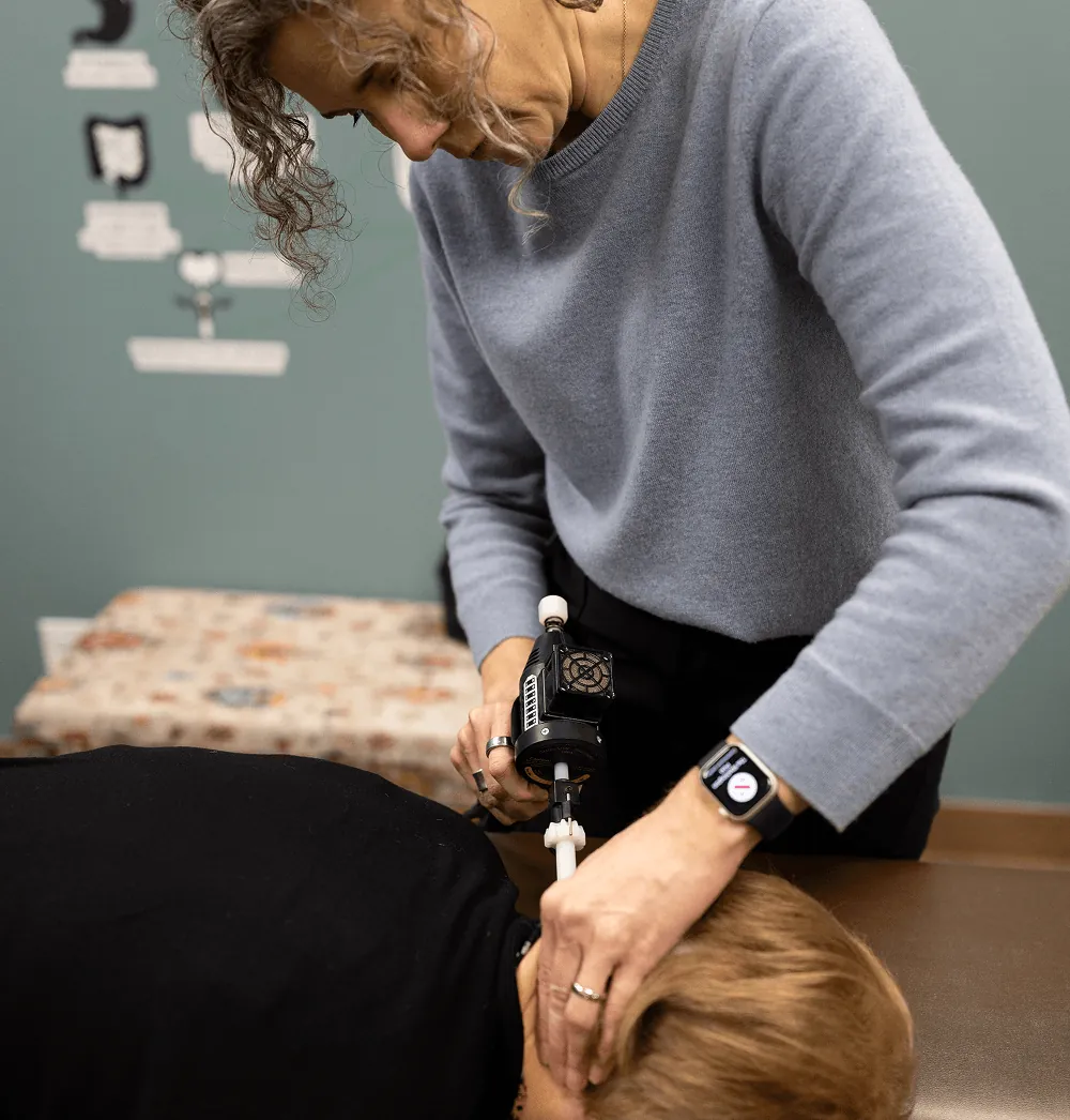 Dr. Stacy using an Activator near a patient's neck