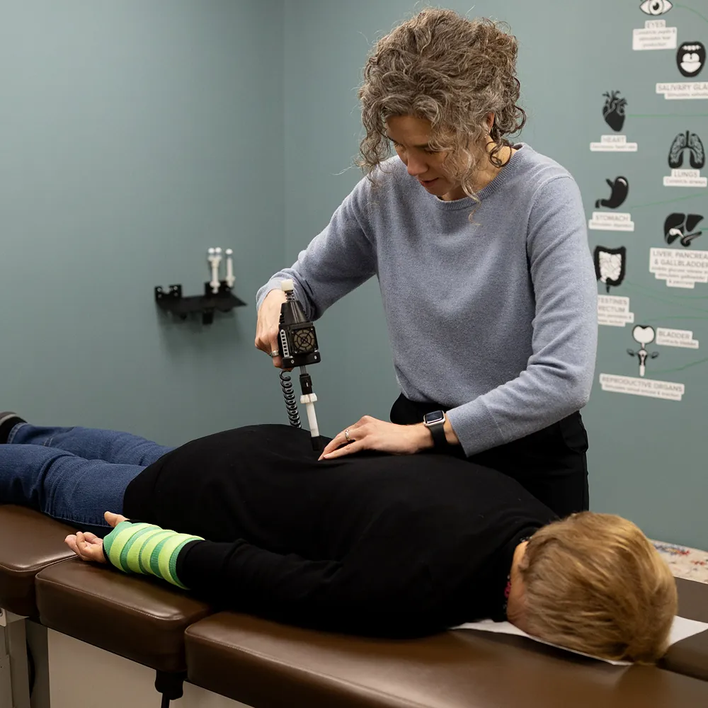 Dr. Stacy using an instrument adjusting tool on a patient's mid back