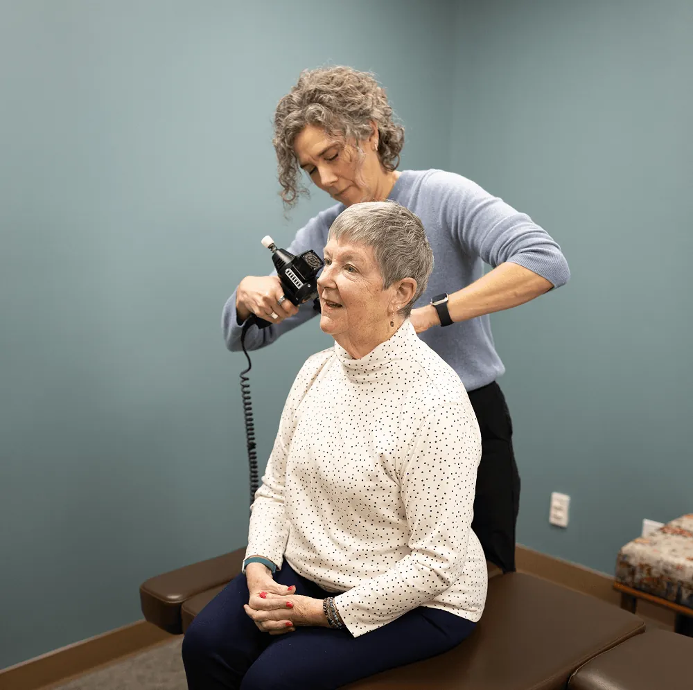 Dr. Stacy using an adjusting instrument on a seated senior patient