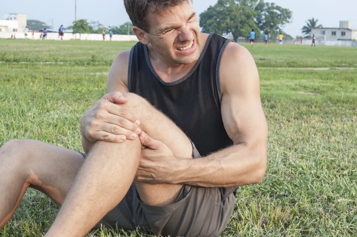 Athlete sitting in the grass with a knee injury