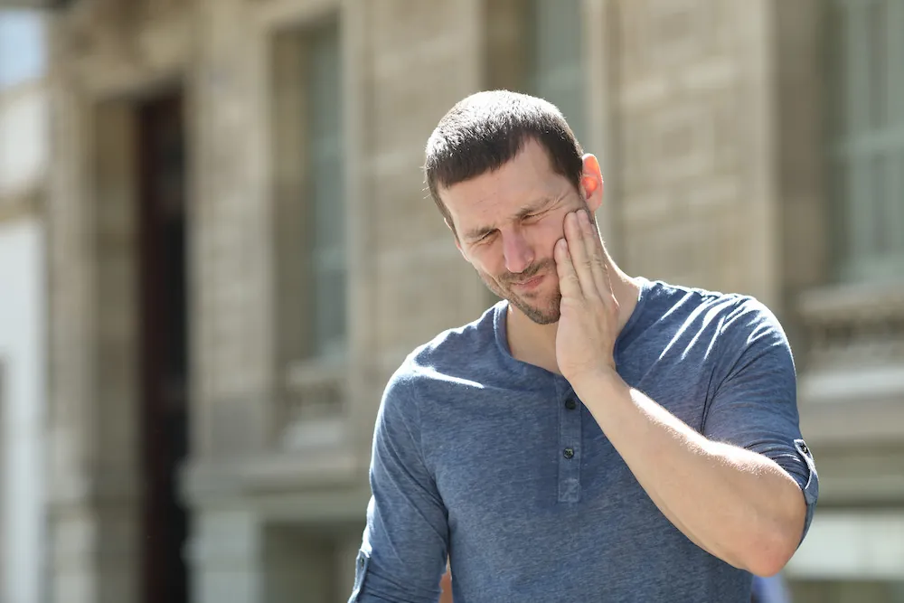 Man holding his jaw with TMJ pain