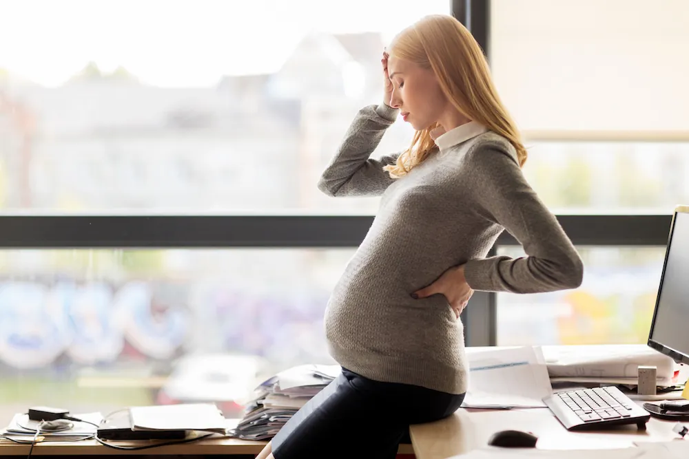 Pregnant woman with back pain at her desk